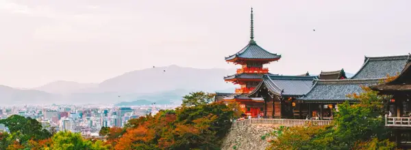 Widok na pagody i tradycyjną architekturę w Kioto, które kiedyś było stolicą Japonii. W tle rozciąga się miejski krajobraz.